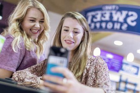 Two female students smiling at cafeteria 